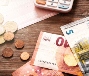 Image d'illustration d'article sur les changements légaux liés à l'immobilier et le logement. Billets euros et calculatrice sur une table, avec une lumière douce et dorée