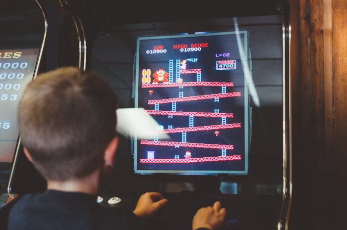 kid playing an old school arcade game