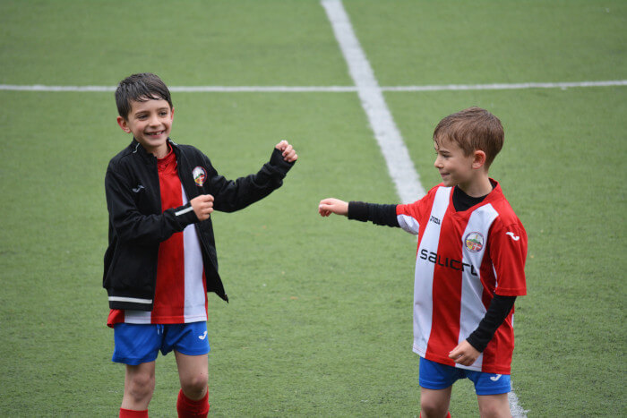 two kids in their soccer uniforms giving props to eachother