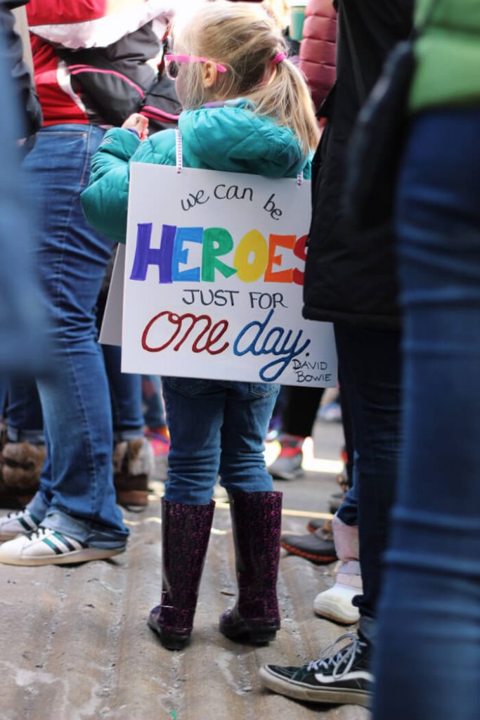 girl at a protest with a cardboard on her back