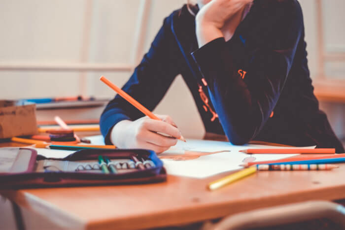 girl taking notes sitting at her school desk