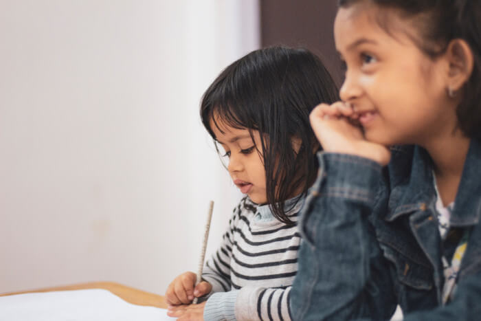 two girls working together on a project one writing the other looking upfront