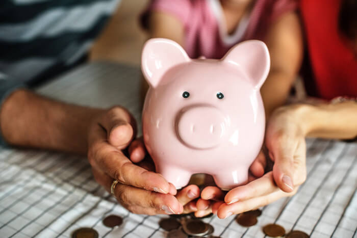 hands holding a piggy bank with pennies under