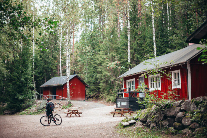 red cabins in the woods with a man standing next to his mountain bike