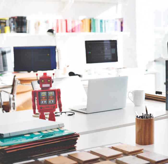 Oficina con computadoras y un robot de juguete en el escritorio.