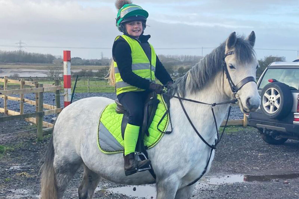 Grey pony and rider wearing high vis safety gear