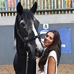 International Dressage Rider Gemma Owen - a brown haired woman stood next to a black and white horse smiling at the camera