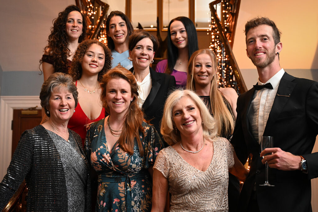 A group of ten people stood staggered on a staircase in black tie attire smiling at the camera.