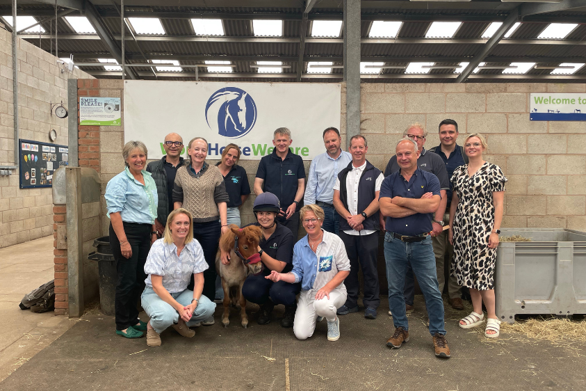 a group of people posing for a photo together at World Horse Welfare Penny Farm with a Shetland pony