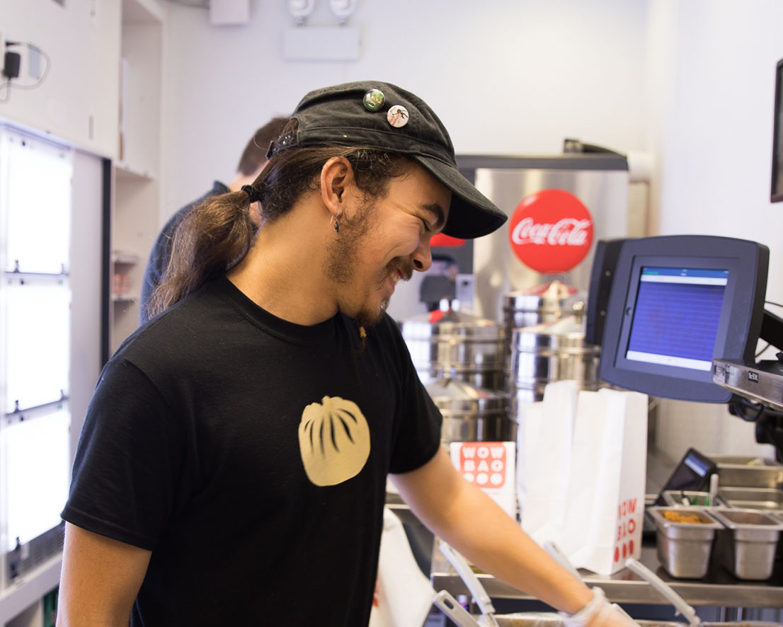 A Wow Bao team member wearing a Wow Bao tshirt is smiling while tending to an order.