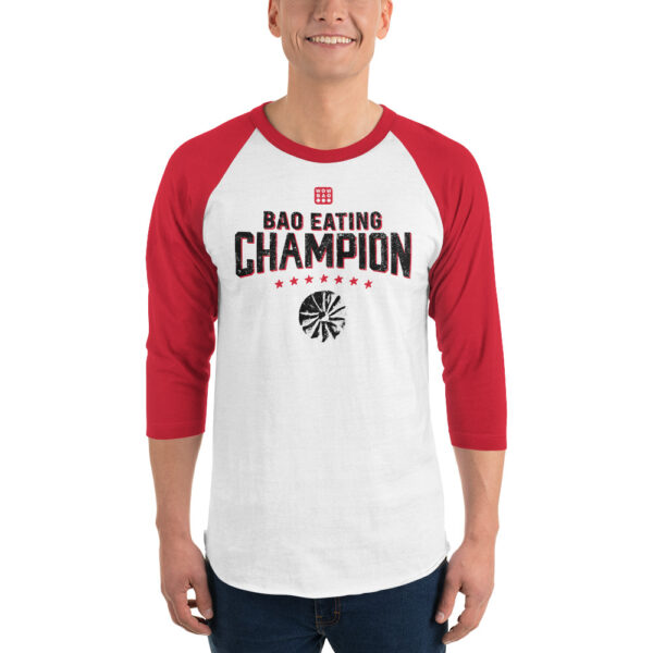 A male presenting person wearing a 3 quarter red sleeve baseball tee, saying "BAO EATING CHAMPION" in large font with stars and a grunge-y bao illustration below it