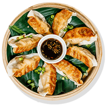 8 potstickers with dipping sauce in a wooden basket steamer