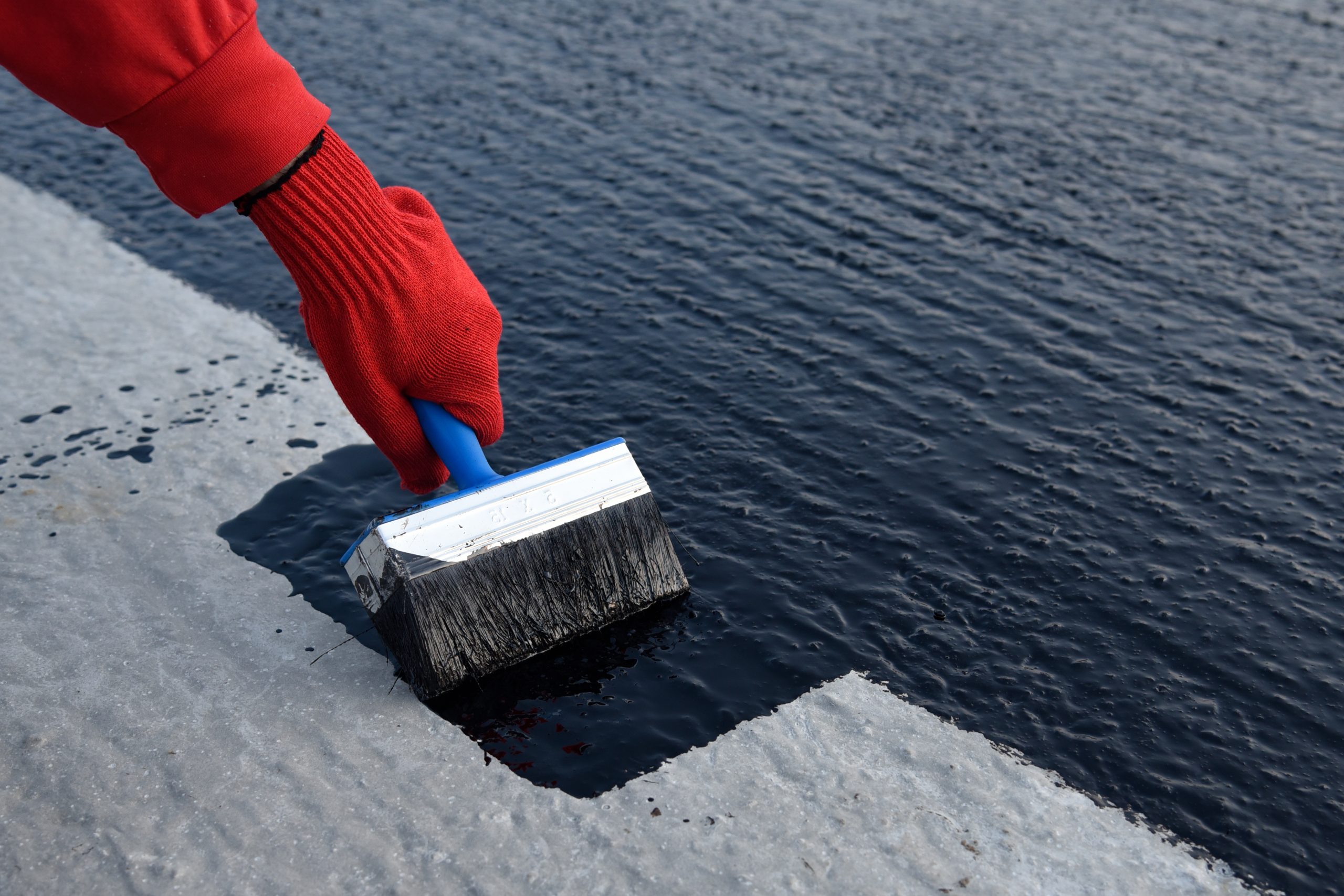 Applying Waterproof paint bitumen with big paintbrush