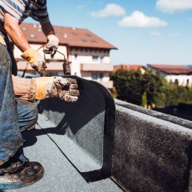 construction worker installing and waterproofing flat roof