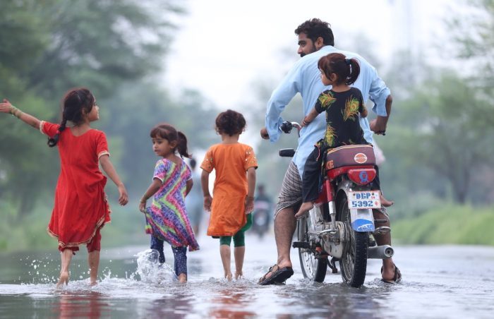 A family escapes the floods with the father and daughter perched on a motorbike.