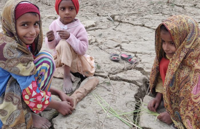 3 little girls playing on the mud-encased fields devasted by the flood waters near Rajanpur, Punjab, Pakistan.