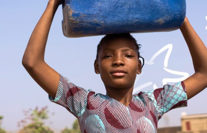 Girl carrys water container on her head in Africa