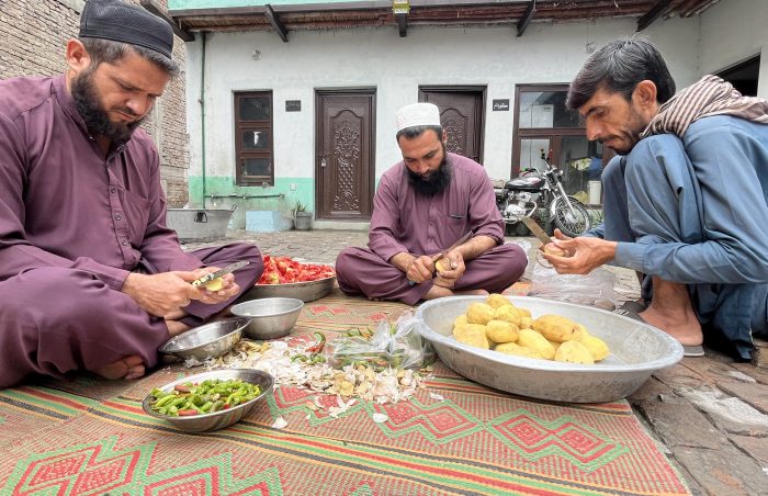 3 men prepare the veg for a cooked Walima dinner for 400 persons in Afghan.