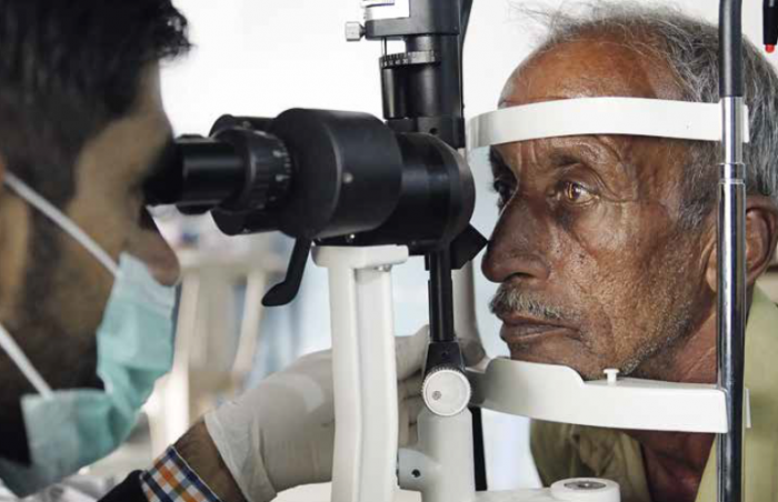 elderly man on machine eye with doctor examining the back of the eye