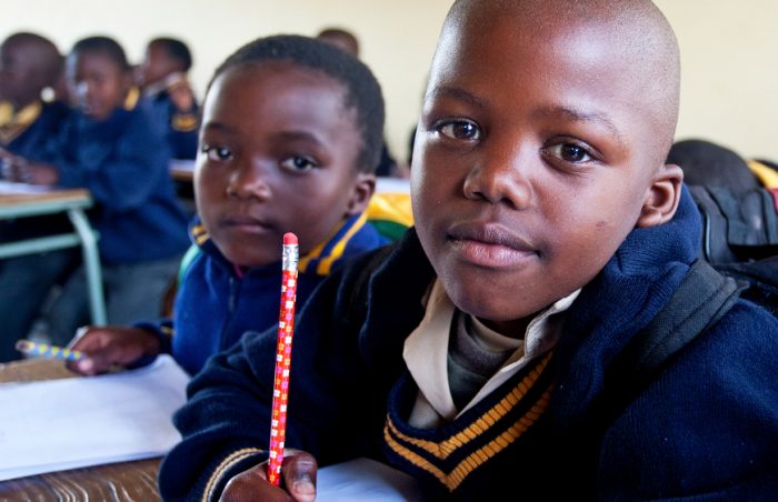 An orphan from Swaziland sits at his school desk dressed in uniform amongst a class of students
