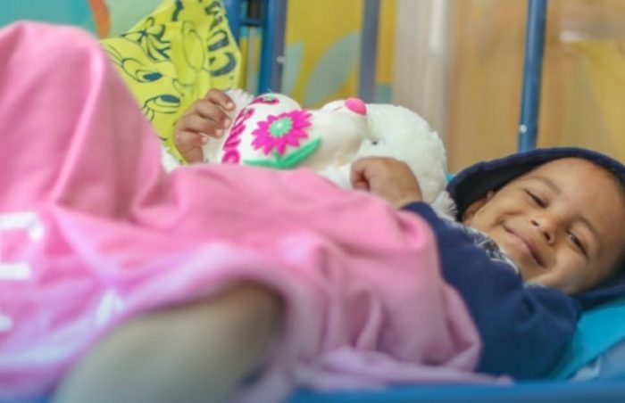 A smiling child lies on his hospital bed after cancer treatment in Gaza, Palestine