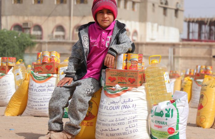 Food pack distribution in Yemen, with child in pink hat and scarf