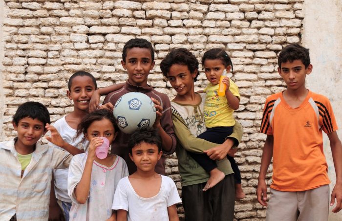 A group of arab children play footbal and line up against a wall in Sanaa, Yemen