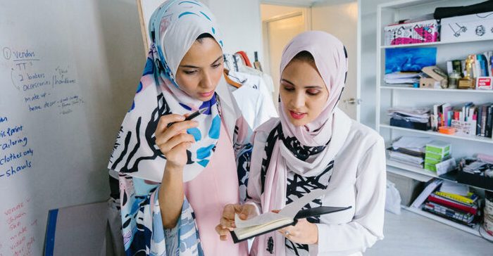 2 muslim women in white hijabs discussing fundraising ideas in the office