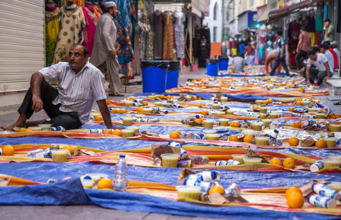 Pakistani man sits patiently in street with iftar food laid out awaiting Maghrib during Ramadan in UAE