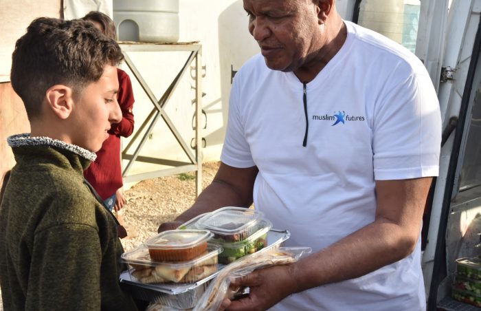 Cooked and pre-packed food being handed to a Syrian refugee boy in Lebanon resized