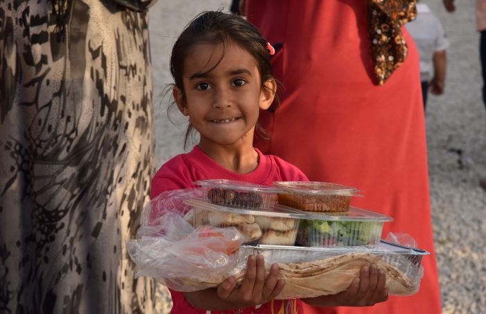 Syrian girl in red dress gets cooked pre-packed food in Lebanon