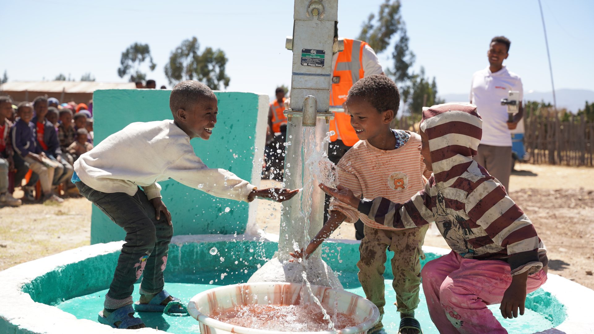 Children filling containers at a new water well