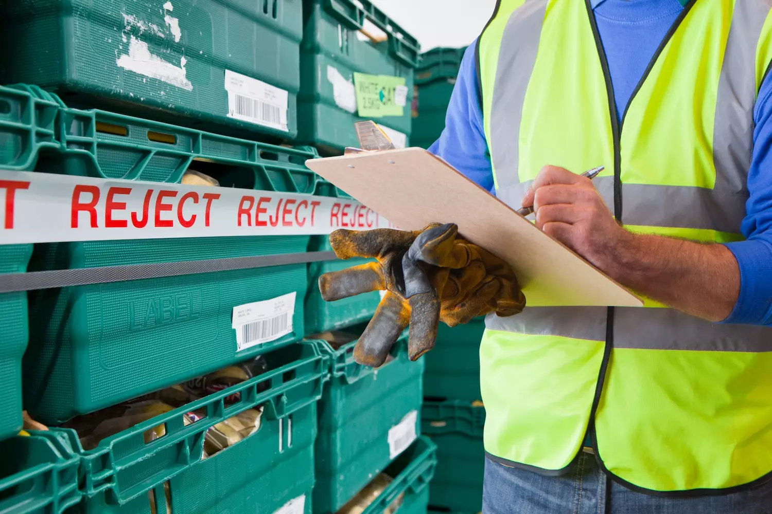 Worker inspecting condemned foodstuffs for disposal