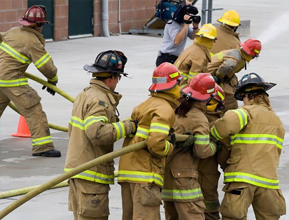 Grupo de bomberos en formación sosteniendo una manguera durante un ejercicio de entrenamiento