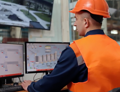 Técnico en una sala de monitoreo revisando pantallas de control de procesos y seguridad
