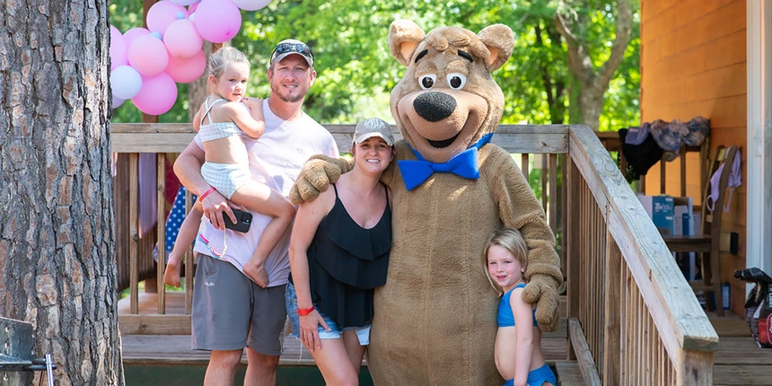 A camping family with the famous Boo Boo™ Bear smiling at the camera.