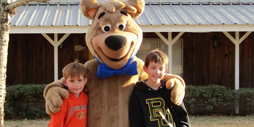 Two boys posing with Boo Boo™ Bear and smiling at the camera.