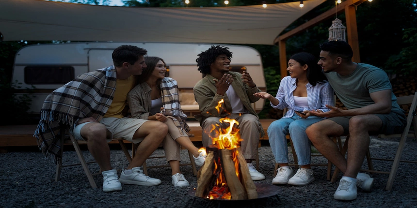 A group of friends having fun around a campfire while RV camping 
