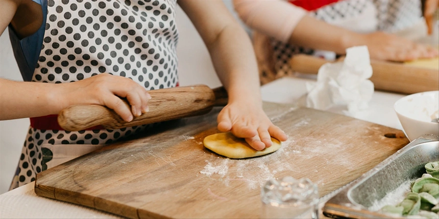 Child cooking on a cutting board and making a pastry.