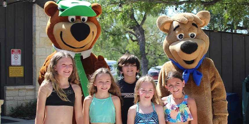 Yogi Bear and friends posing with a group of campers. 