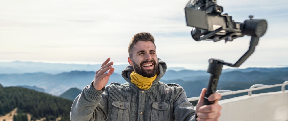 Travel influencer filming a vlog in front of some scenic mountains