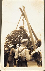 Stripped African American male stretched on a tripod rack, raised with pulley, upper body bandaged, lower body wrapped with a blanket tied with rope, fingers curled involuntarily. Circa 1900, St. Louis, Missouri.