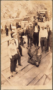 Corpse of Leonard Woods prostrate on speakers platform, white mob.