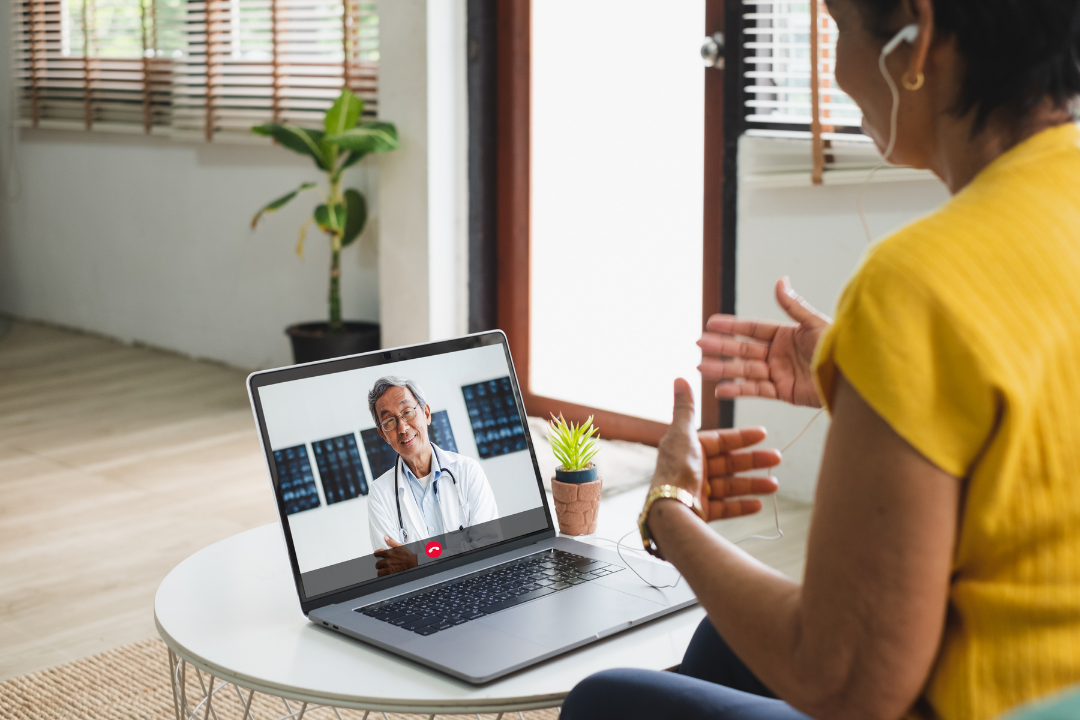 A woman uses her laptop to have a video appointment with her doctor.