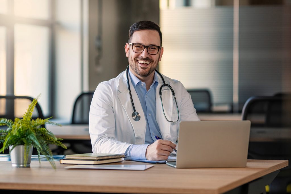 Smiling man working in the medical industry at his laptop