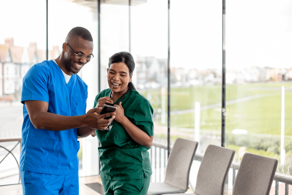 Two medical professionals smiling at a phone
