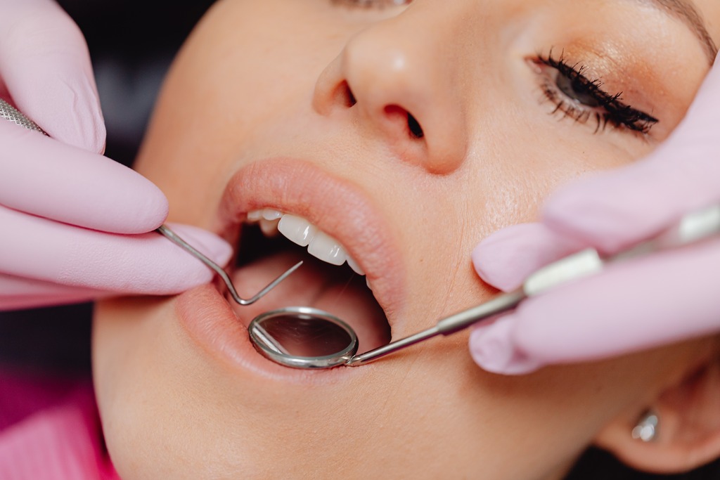 close up of dentists hands holding utensils inside a patients mouth
