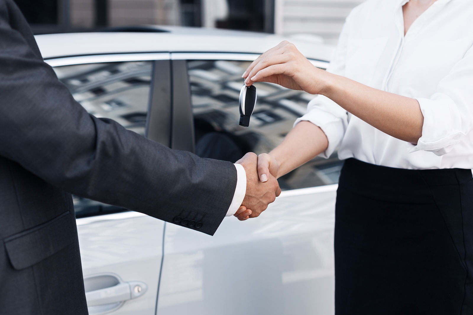 Customer and salesperson shaking hands and exchange a set of car keys