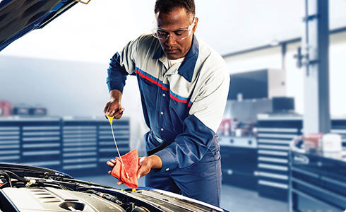 mechanic checking the oil of a car