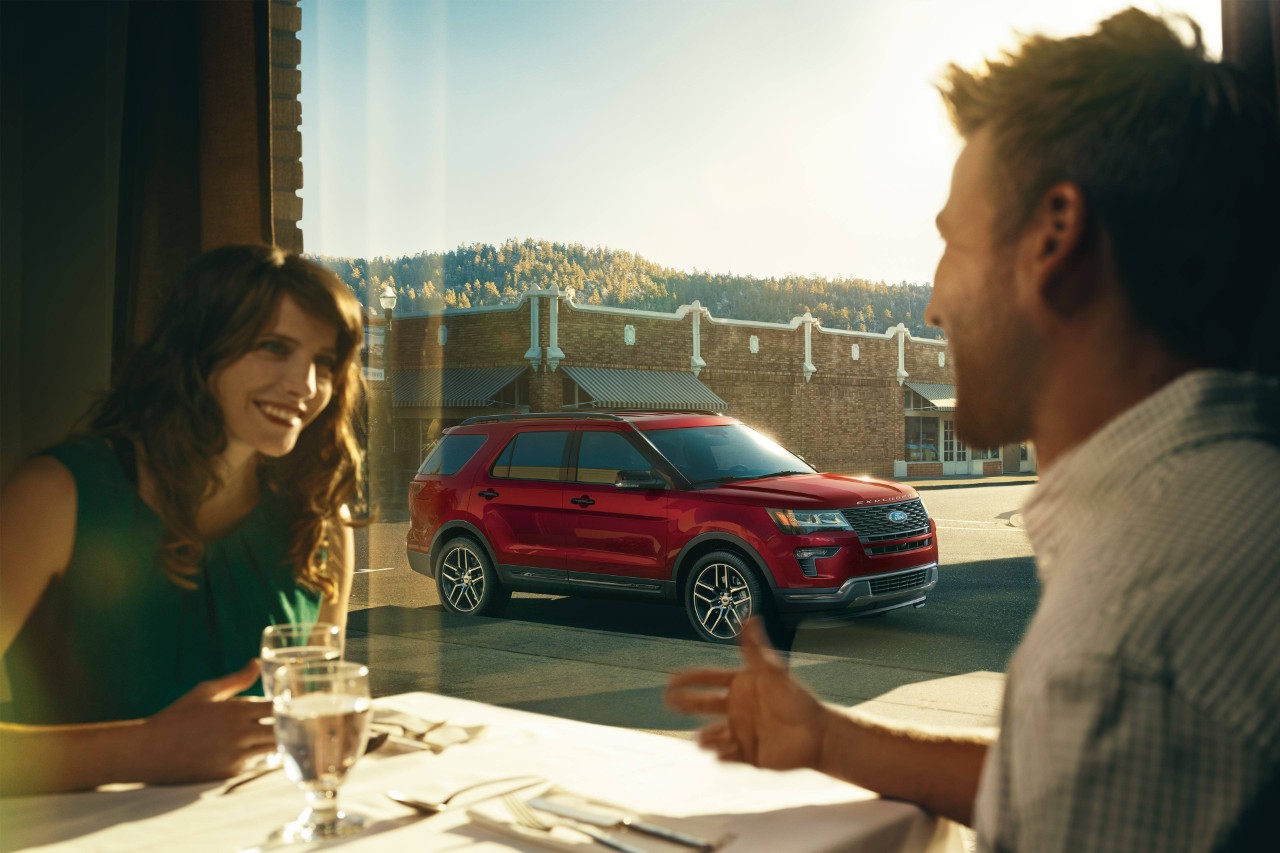 couple eating in a restaurant with their red 2019 ford explorer parked outside